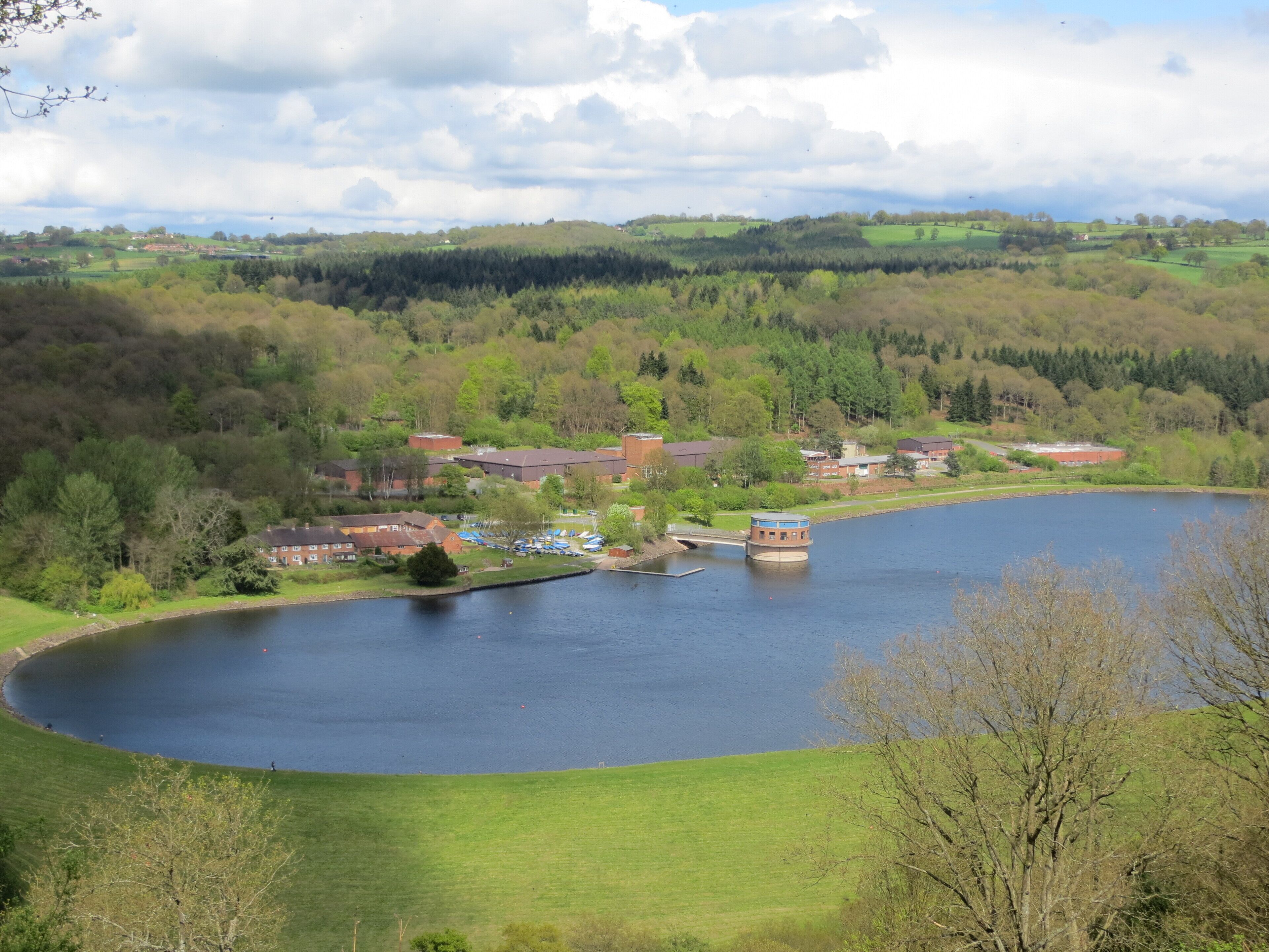 A lake surrounded by green hills and buildings.
