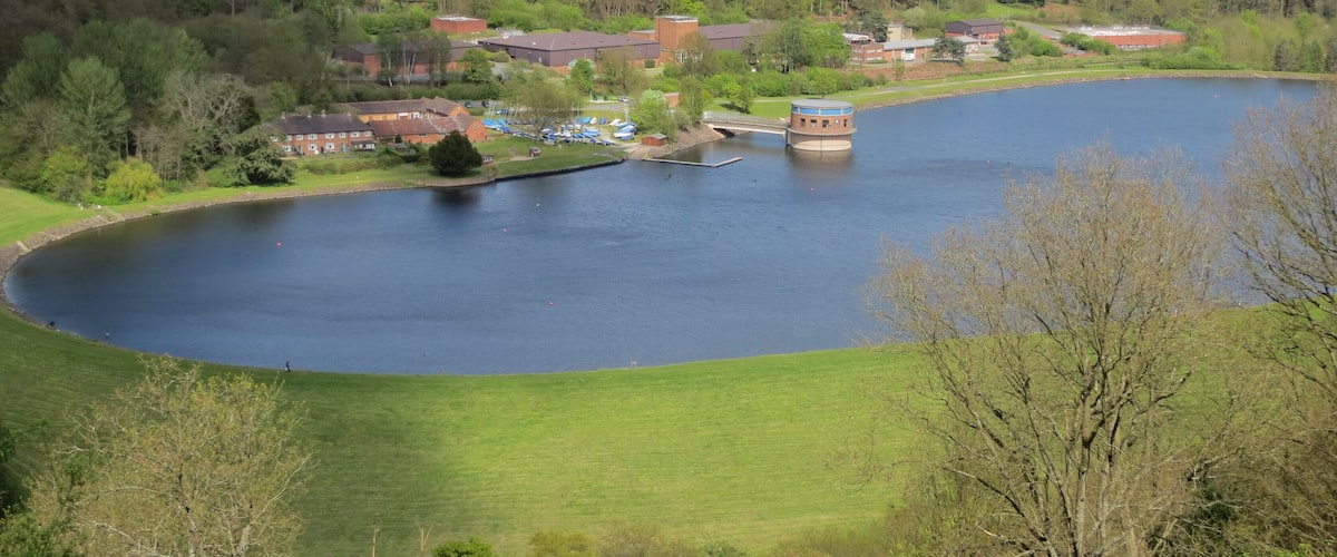A lake surrounded by green hills and buildings.