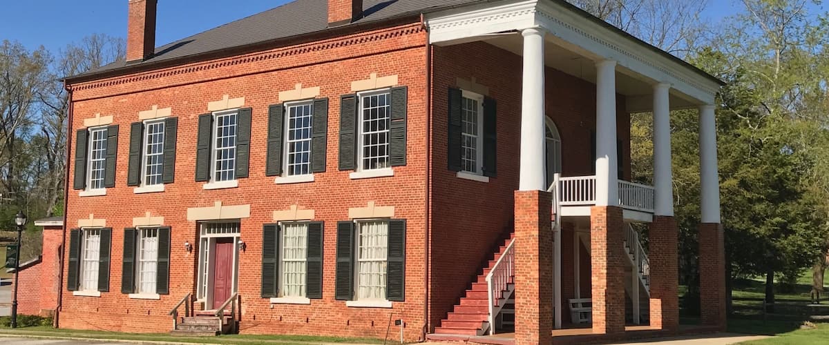 A red brick building with white columns and a covered porch.