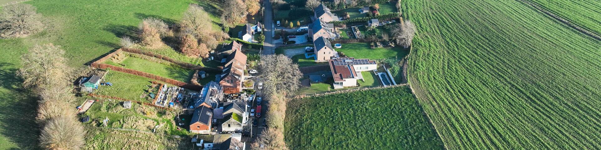 An aerial view of a rural village with houses, fields, and a river.