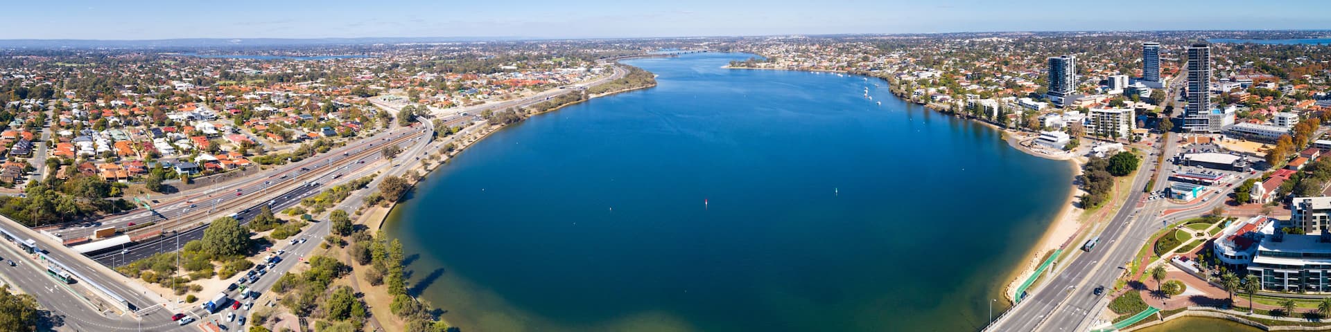 A large body of water surrounded by a cityscape with roads and buildings.