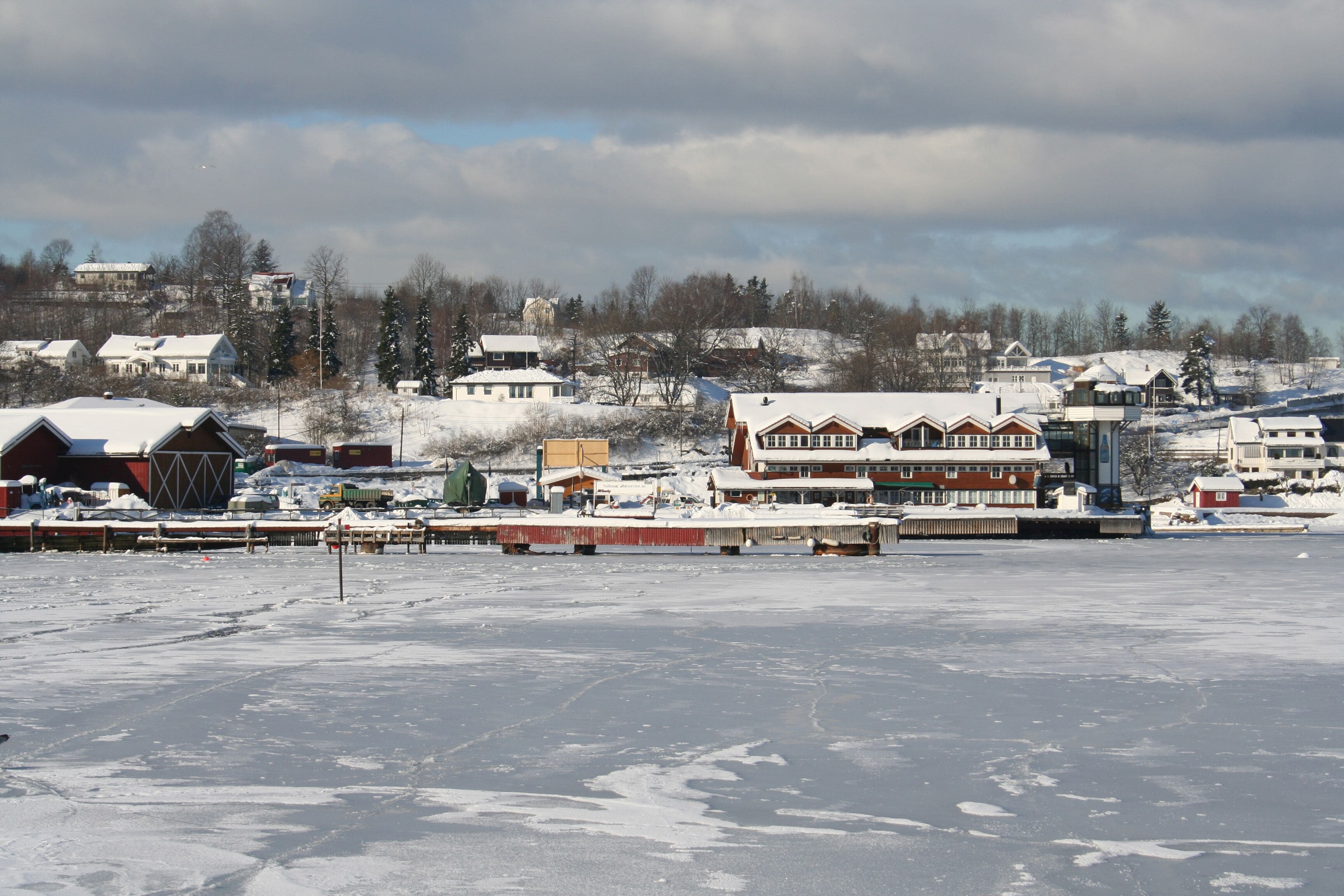 A snowy landscape with houses and a dock.
