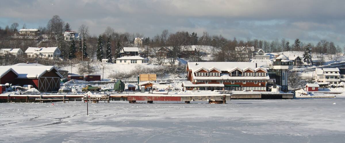 A snowy landscape with houses and a dock.