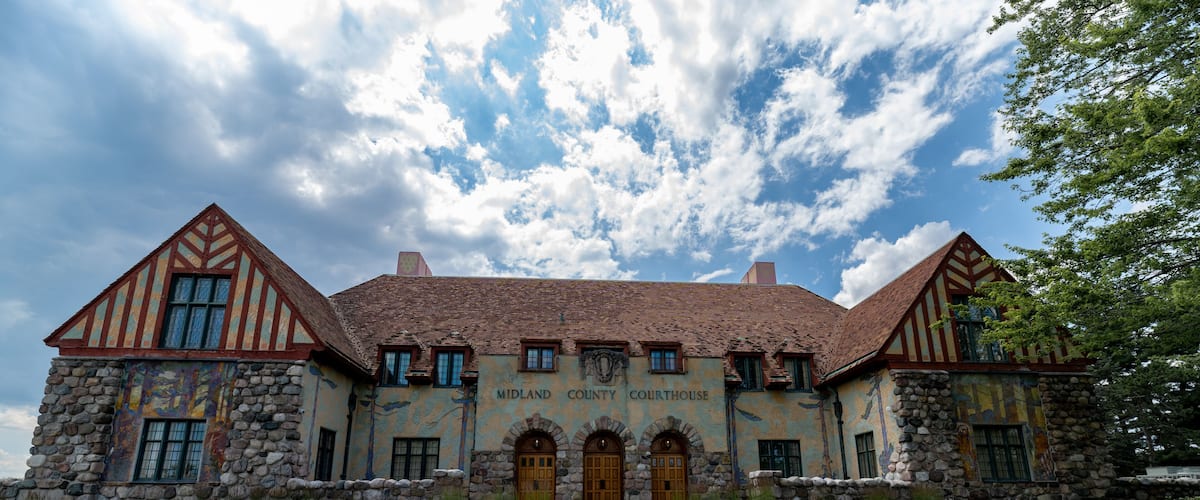 A large stone courthouse with a red roof and timber framing.