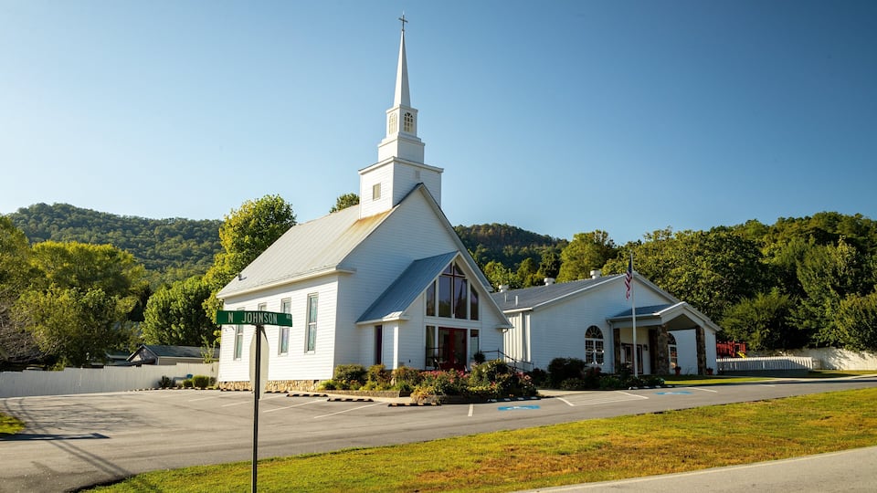 A white church with a steeple and a cross on top, located at N Johnson Ave.