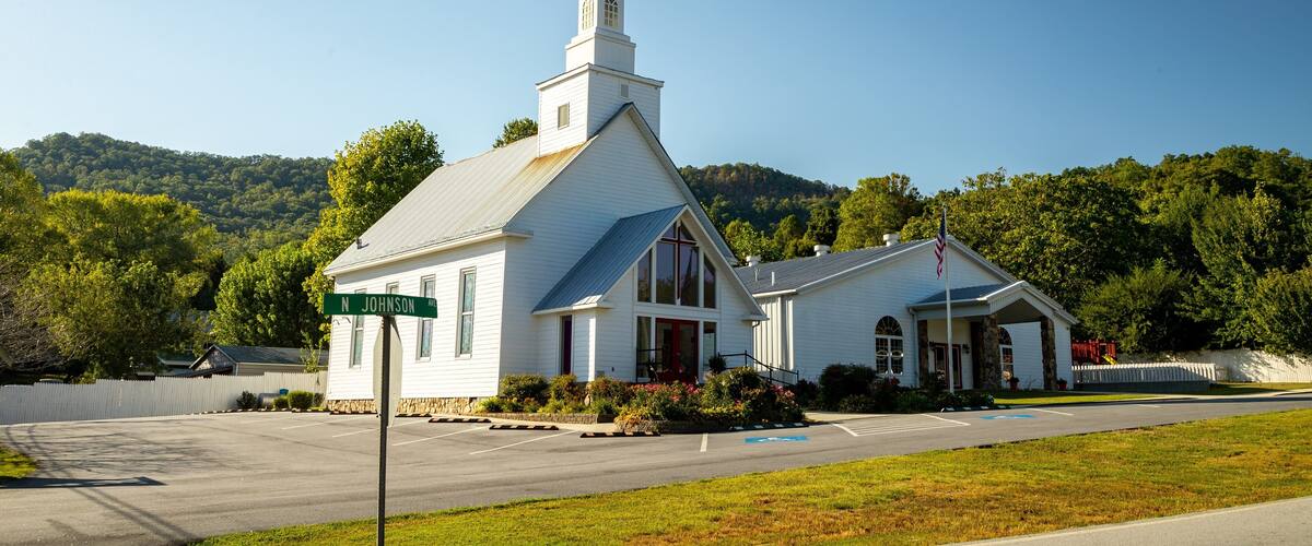 A white church with a steeple and a cross on top, located at N Johnson Ave.