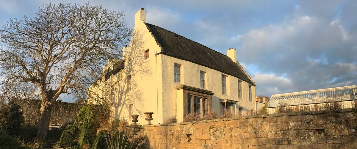 A historic building with a stone wall and a garden.