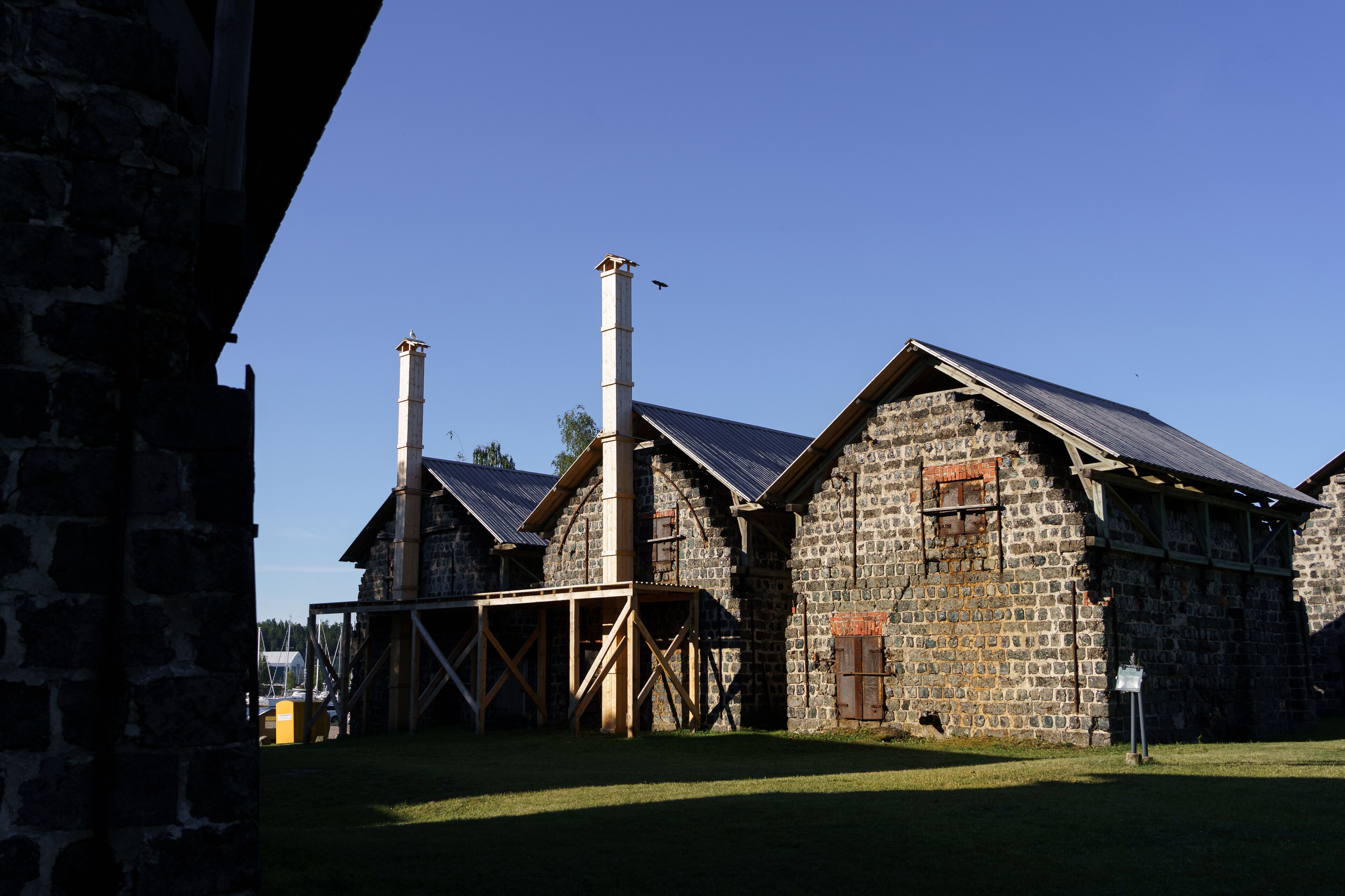 A stone building with a chimney and a wooden structure in front.