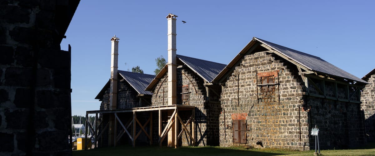A stone building with a chimney and a wooden structure in front.