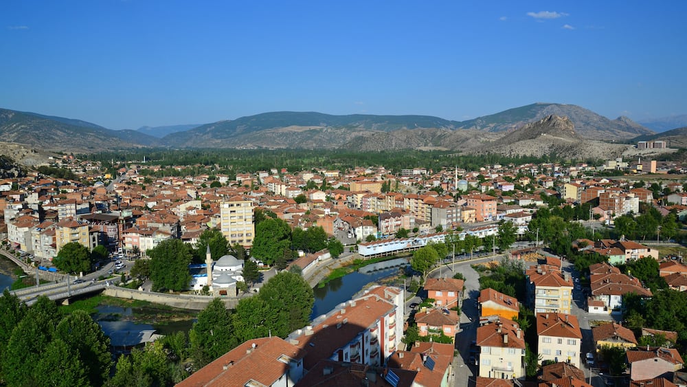 Une ville traversée par une rivière, entourée de montagnes et dotée d’un pont.