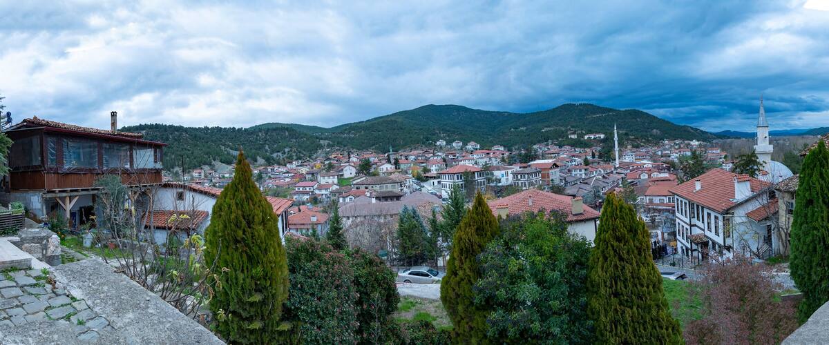 A town with red-roofed buildings, a prominent white church with a tall spire, and surrounding green hills.