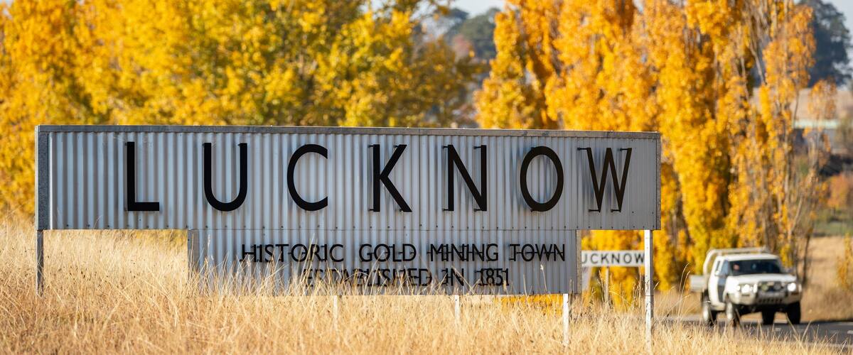 A sign reading "Lucknow Historic Gold Mining Town" with a vehicle in the background.