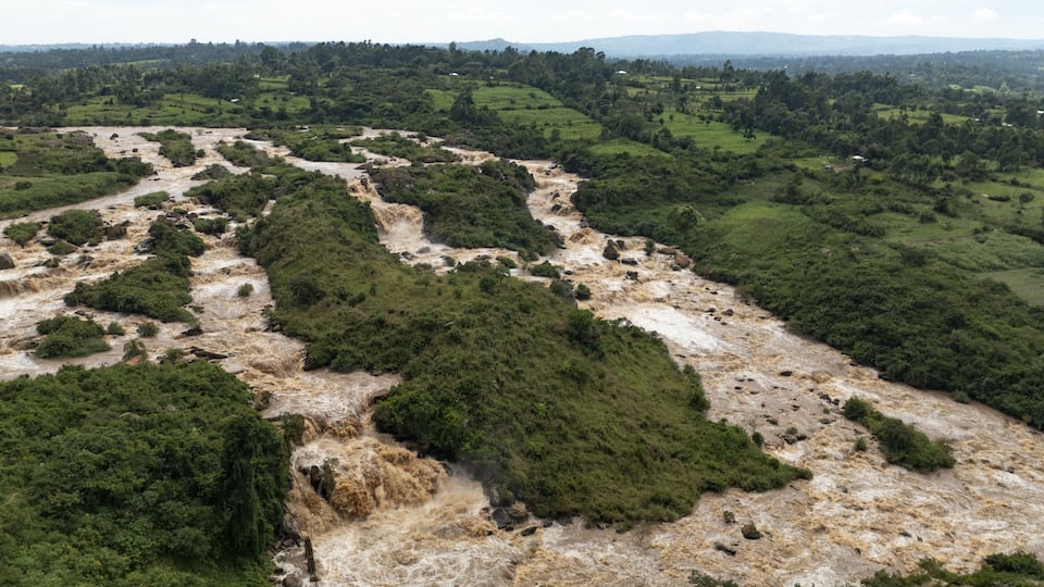 A river winding through a lush green valley with rocky terrain and distant hills.