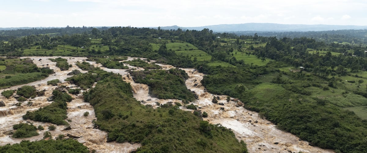 A river winding through a lush green valley with rocky terrain and distant hills.