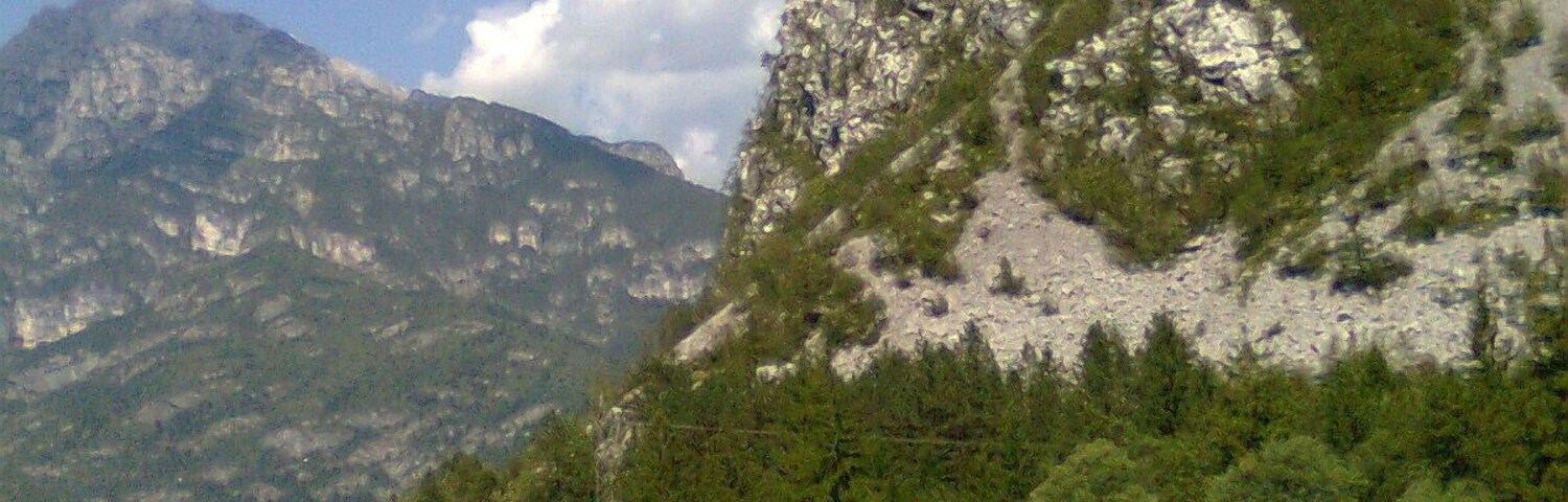Un paisaje montañoso con un río, una barandilla y cielo despejado.