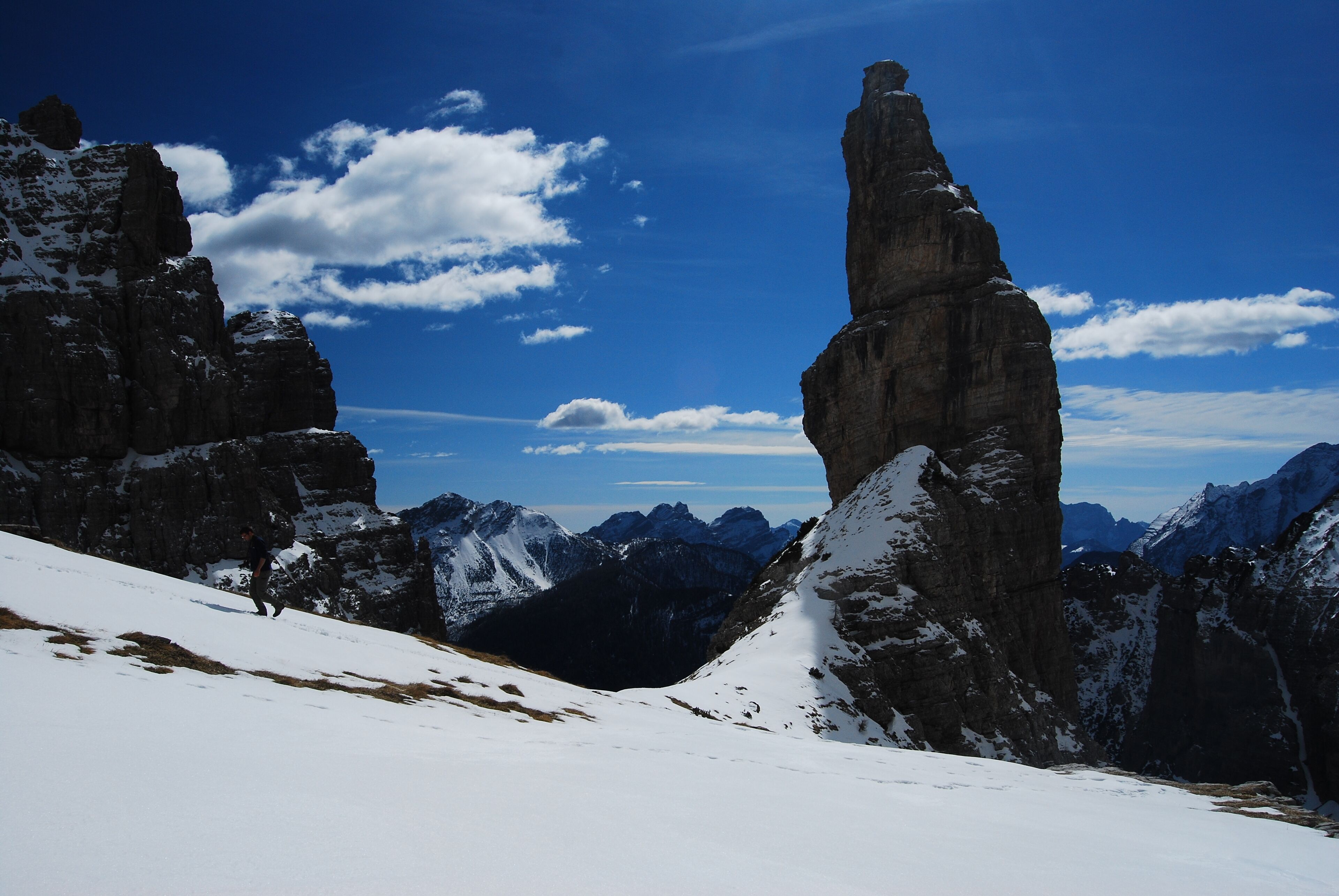A snow-covered mountain landscape with prominent rock formations and a clear blue sky.