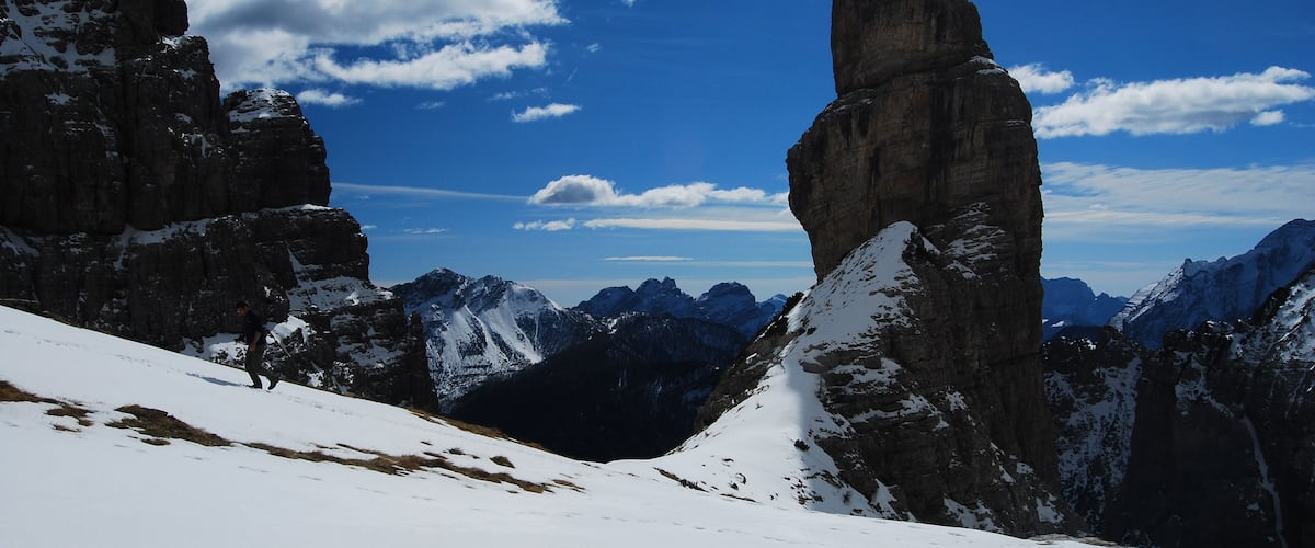 A snow-covered mountain landscape with prominent rock formations and a clear blue sky.