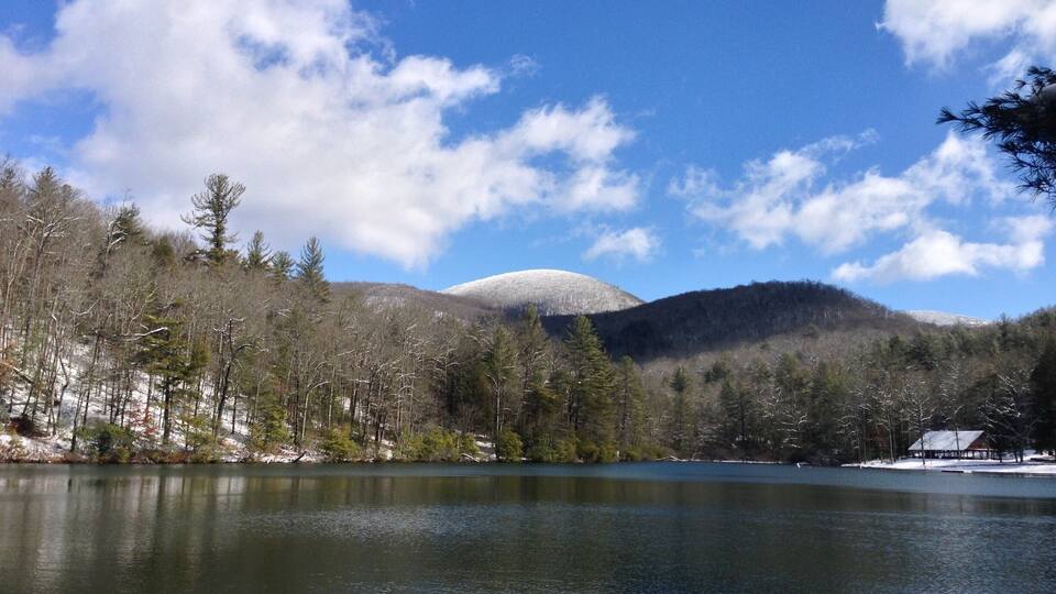 A lake surrounded by trees and hills with a clear sky.
