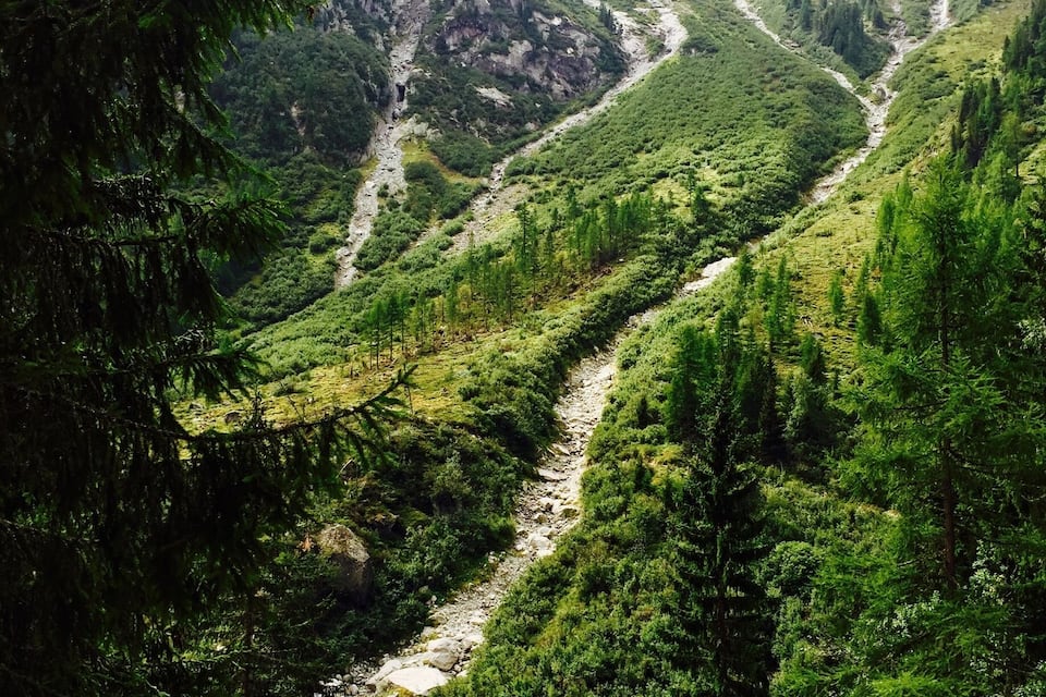 A mountainous landscape with a winding river, dense forests, and rocky terrain.