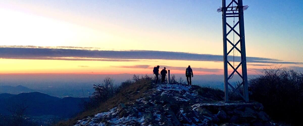 A metal tower on a snowy mountain ridge with hikers in the background.