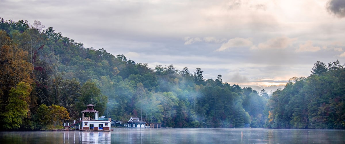 A lake with a row of houses and a forested hillside.