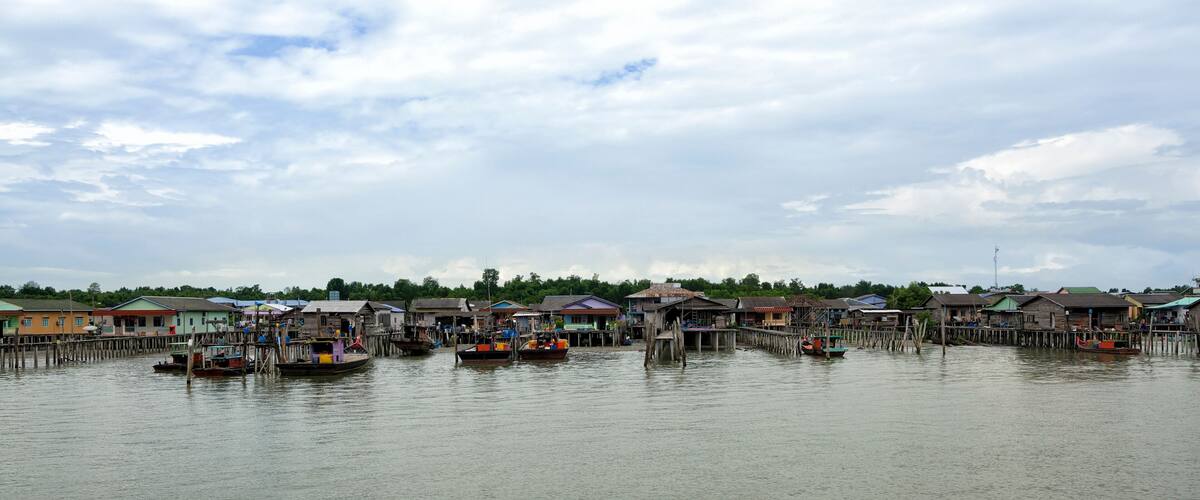 A waterfront village with wooden houses and boats.