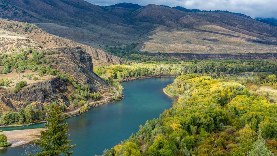 A river winding through a mountainous landscape with dense forests and rocky terrain.