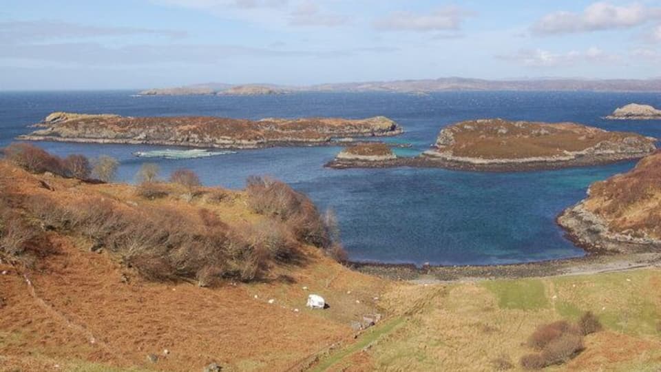 A coastal landscape with rocky outcrops and clear blue waters.