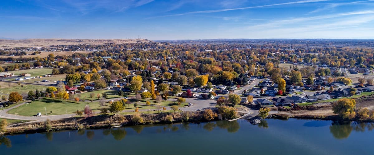 A suburban area with a lake, autumn-colored trees, and houses.