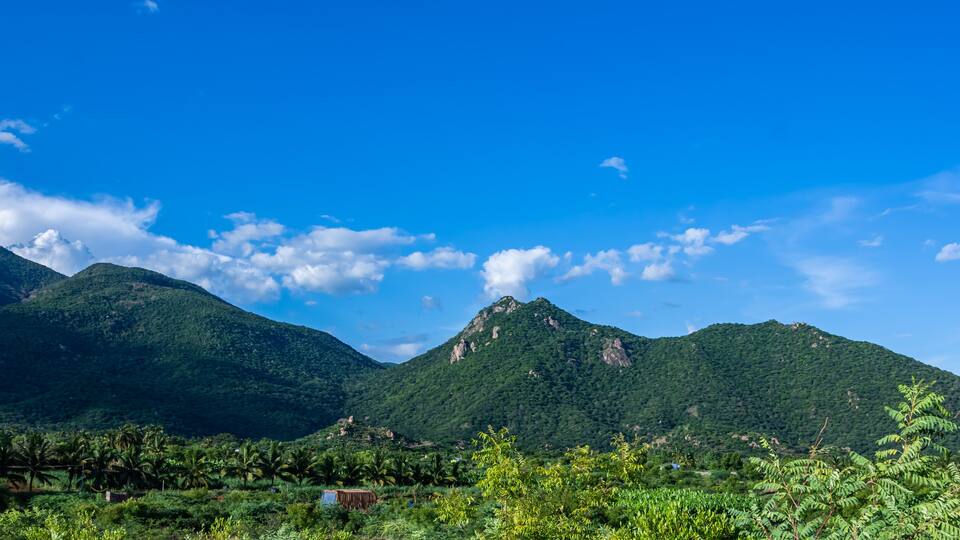 A mountainous landscape with lush greenery and a clear blue sky.