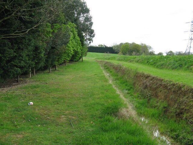 Um campo gramado com uma trilha estreita e um fosso de um lado.