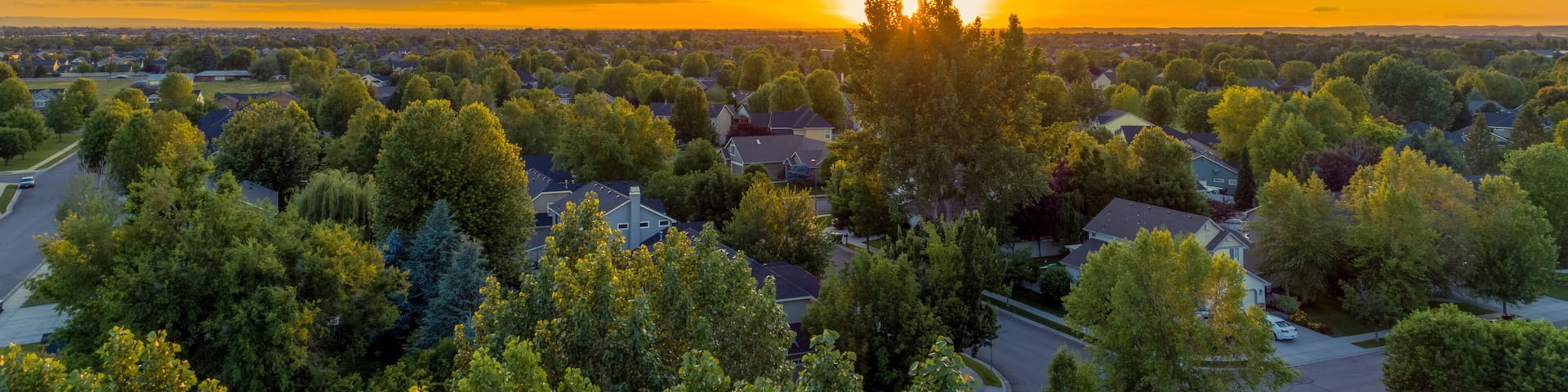 A suburban landscape with a sunset over a residential area.