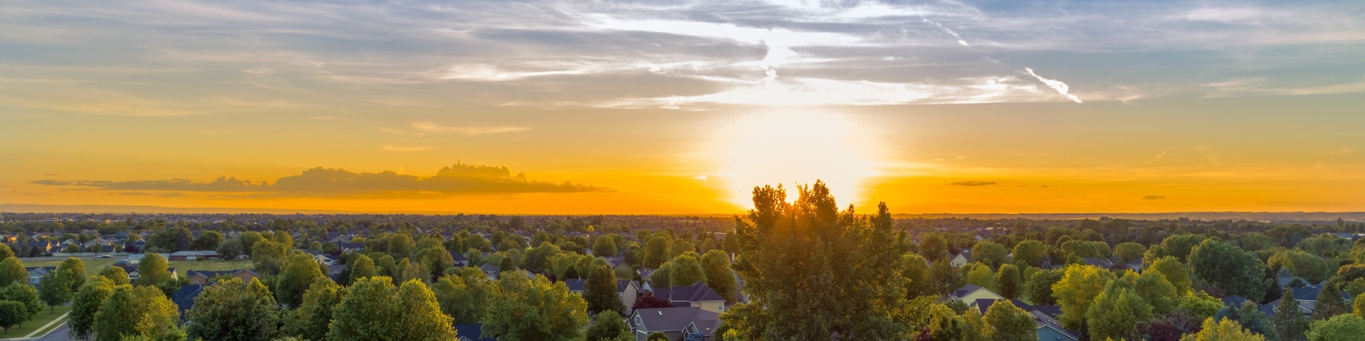 A suburban landscape with a sunset over a residential area.