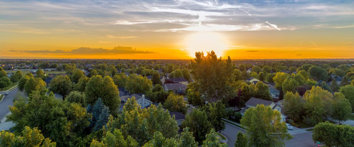 A suburban landscape with a sunset over a residential area.