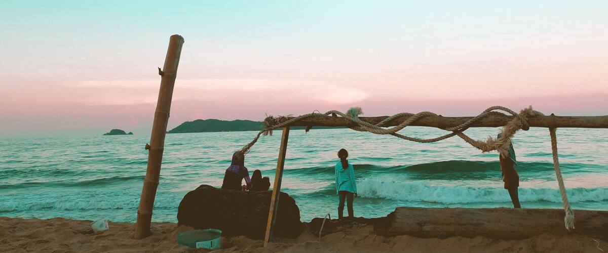 A beach with a wooden structure and people near the water.