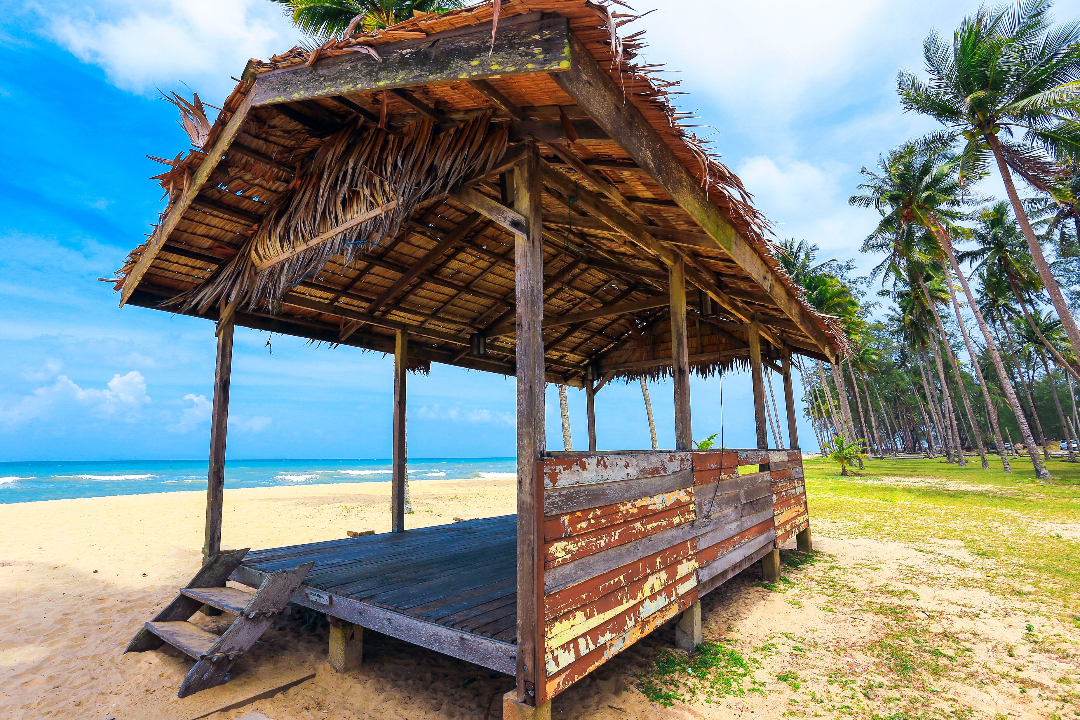 Peaceful scenery of coconut tree and bamboo hut on the ground and blue sky