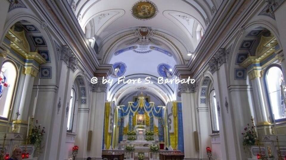 An ornate church interior with high ceilings, arched windows, and a central altar.