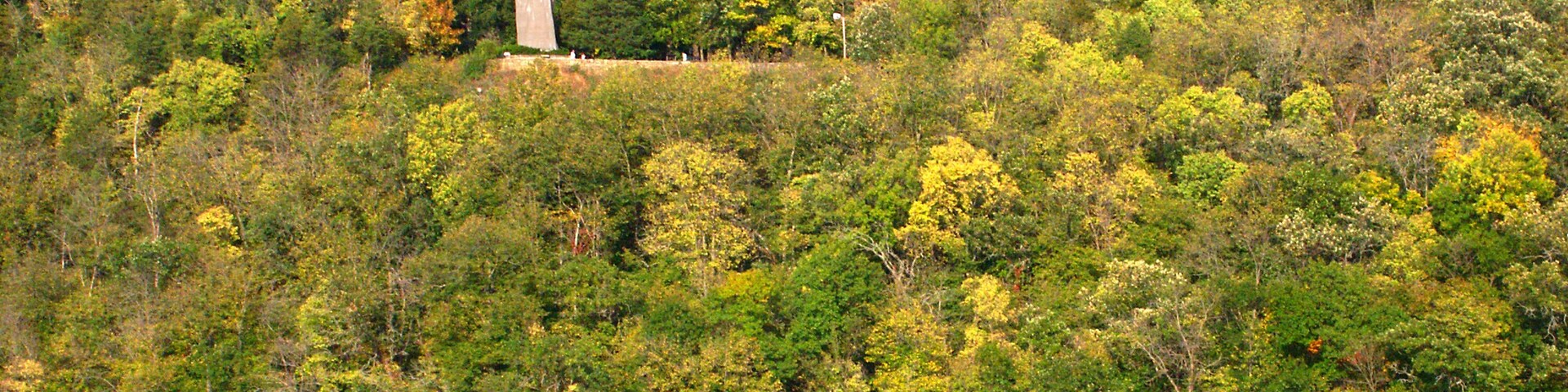 A statue on a hill with a lake in the foreground.