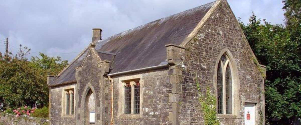 A stone church with a steep roof and arched windows.