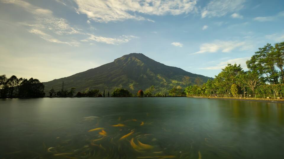 landscape view of mount sumbing sindoro in embung kledung temanggung central java indonesia with an artificial lake and swimming fish suitable for background wallpaper notes and design