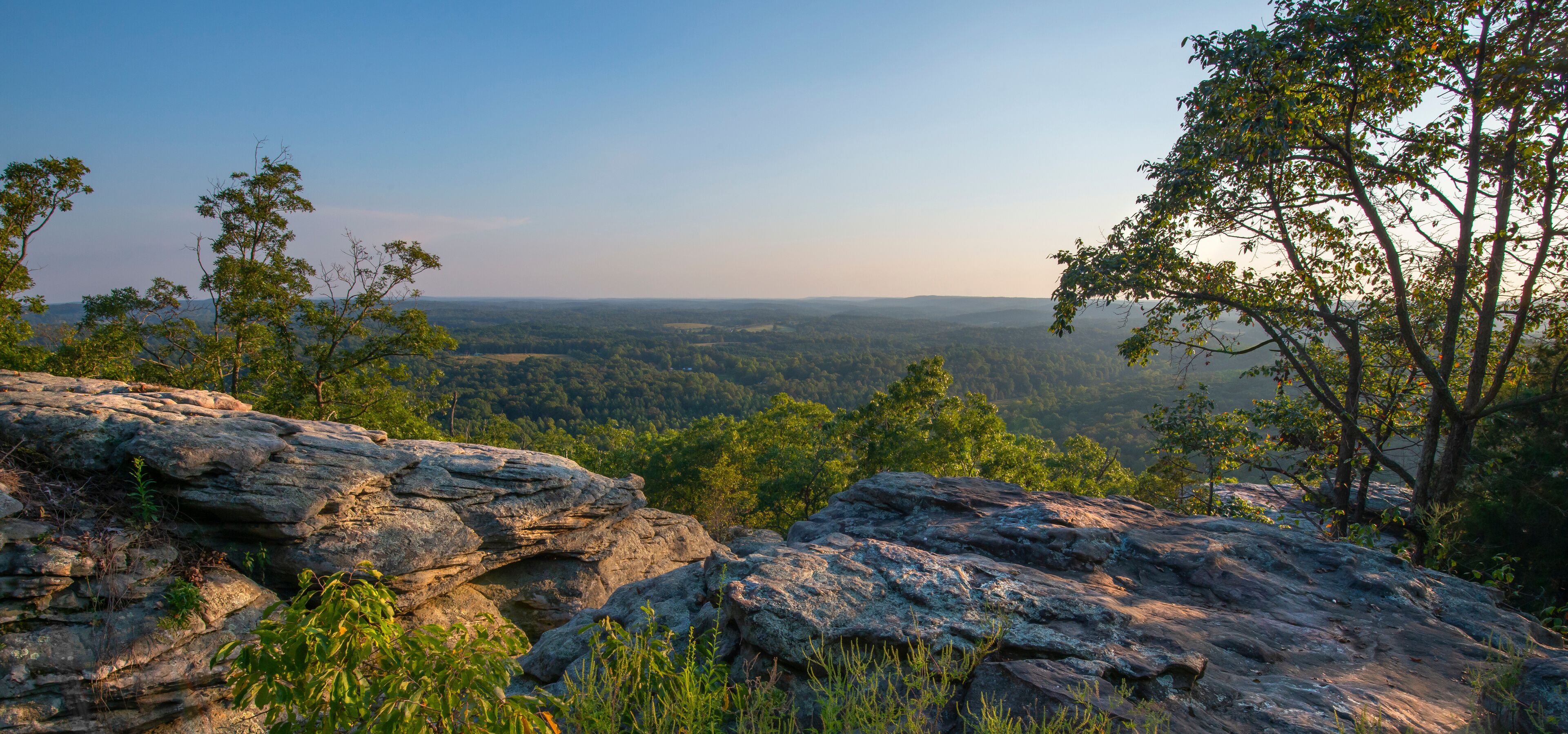 A rocky landscape with a view of a forested valley.