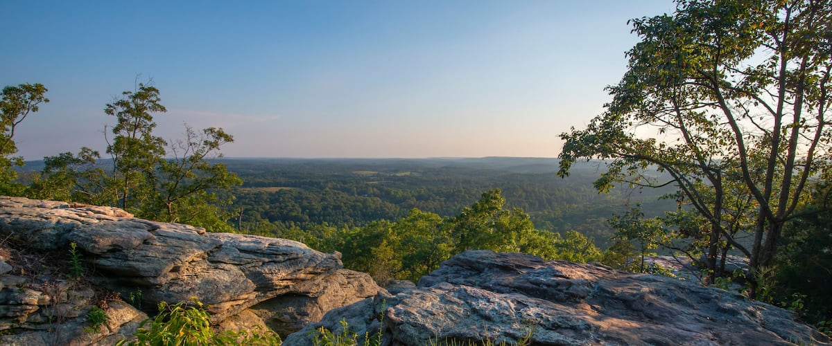 A rocky landscape with a view of a forested valley.