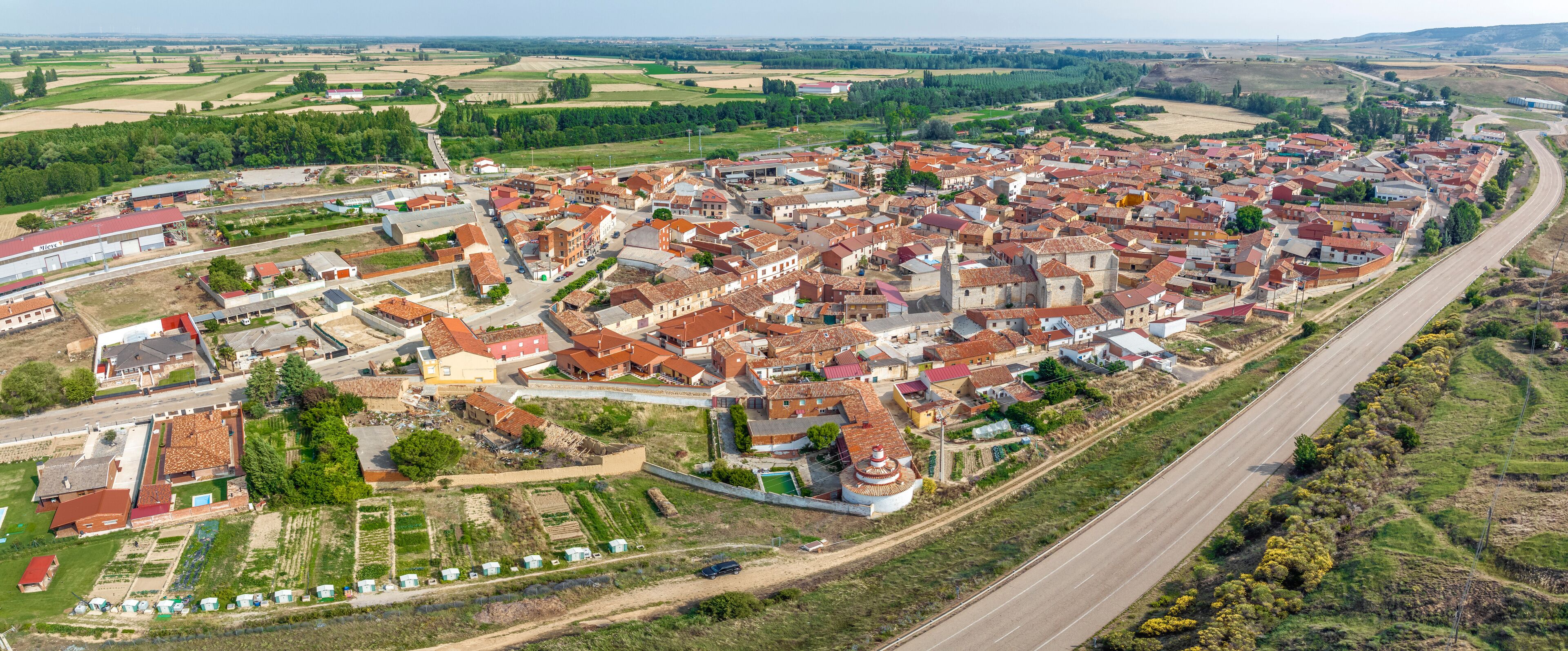 A town with red-roofed buildings, a central church, and surrounding fields.