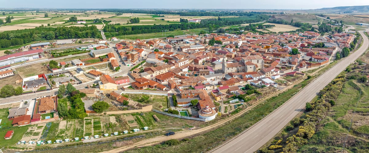 A town with red-roofed buildings, a central church, and surrounding fields.