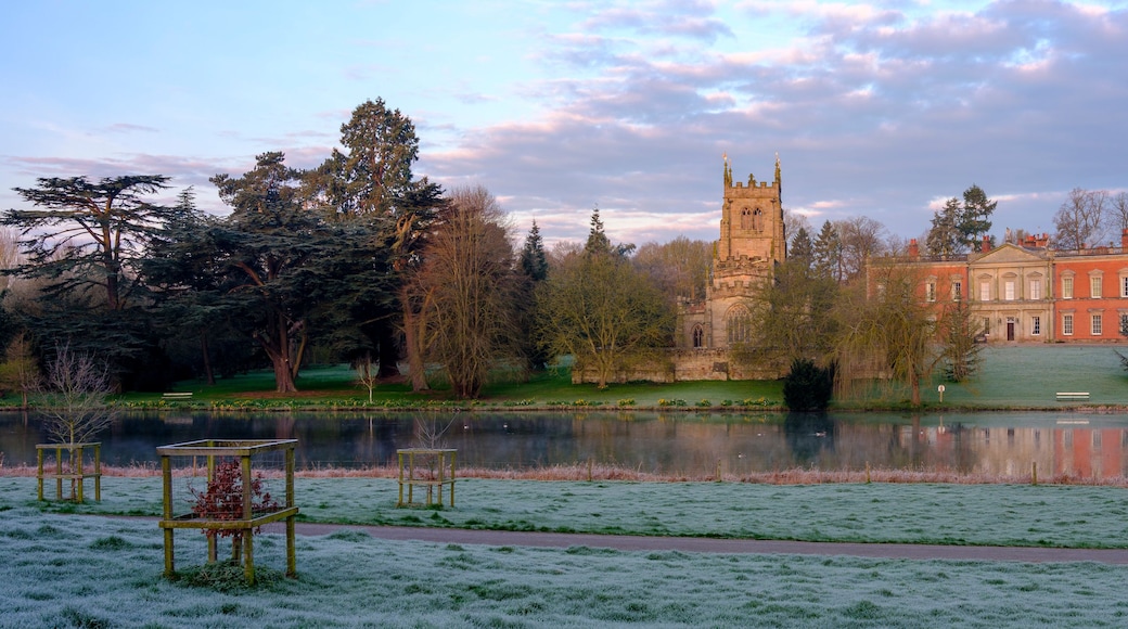 A historic building with a tower, a lake, and frost-covered grass.