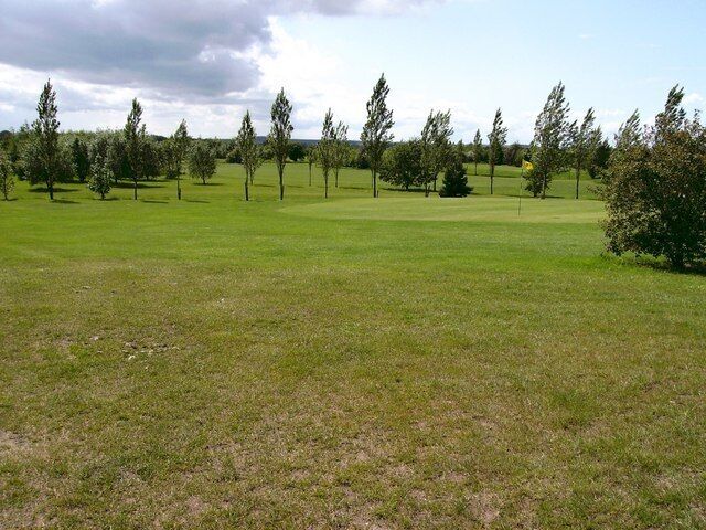 5th Green Surrounded by young trees being blown about by a strong wind.