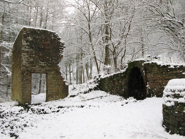 Uma estrutura de pedra coberta de neve numa floresta.