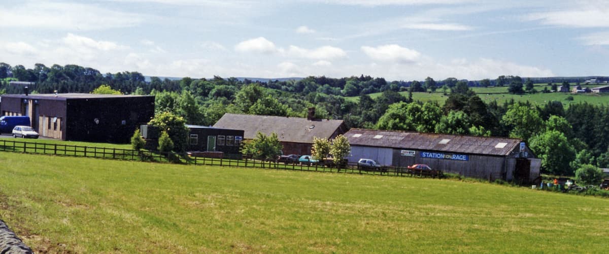 A rural landscape with barns, a fence, and a field.