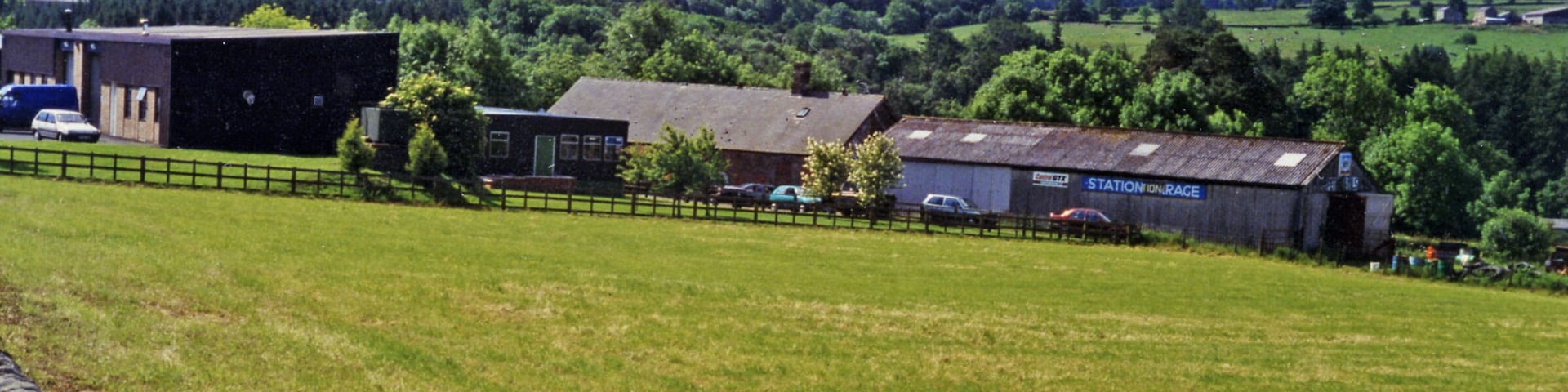 A rural landscape with barns, a fence, and a field.