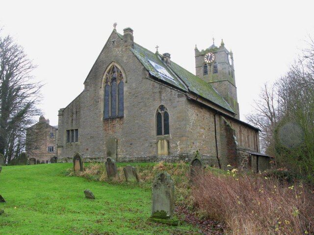 A historic stone church with a clock tower, surrounded by a cemetery with headstones.